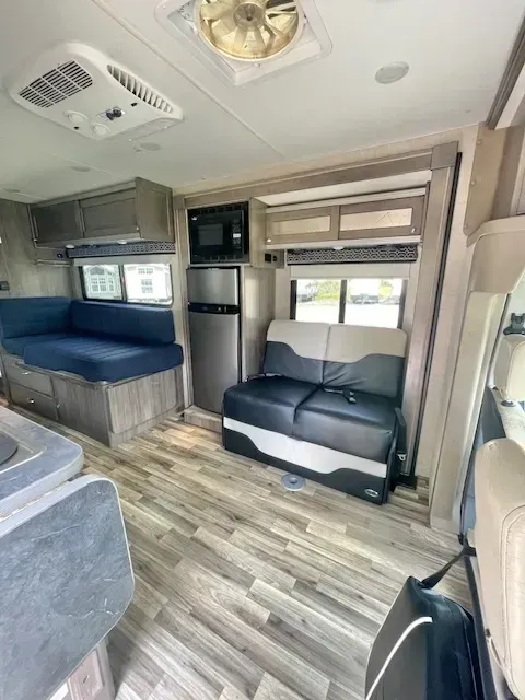 The inside of a rv with a couch and a refrigerator.