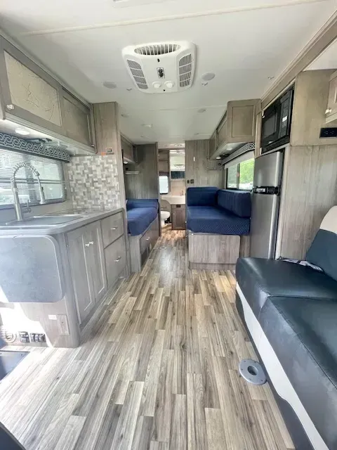 The inside of a rv with a couch , sink , and refrigerator.