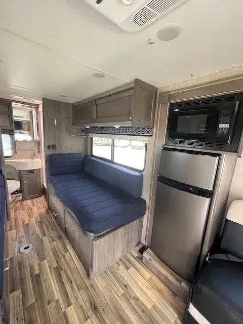 A rv with a couch , refrigerator , microwave and sink.