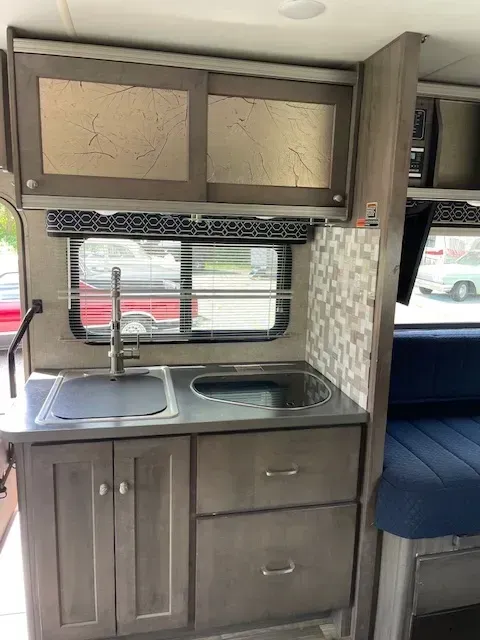 A kitchen in a rv with a sink and cabinets.