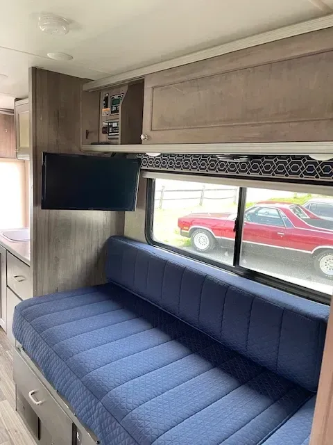 The inside of a rv with a blue couch and a flat screen tv.