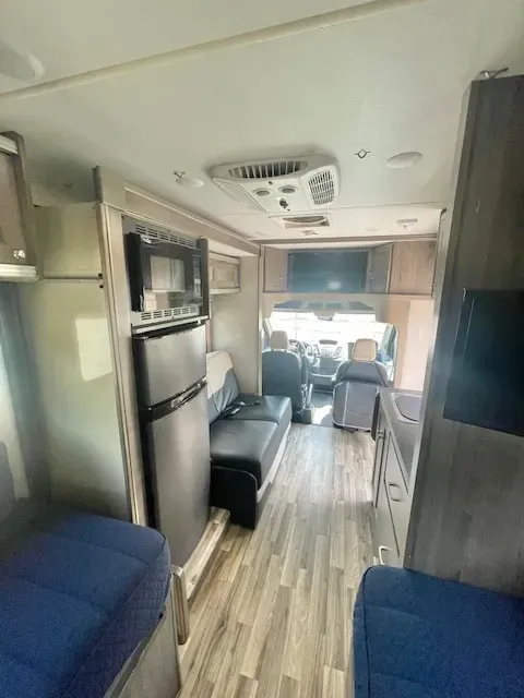 The inside of a rv with a couch and a refrigerator.