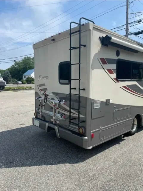 A rv with a ladder attached to the back of it