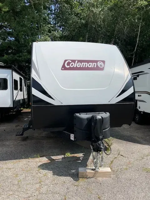 A coleman trailer is parked in a parking lot.
