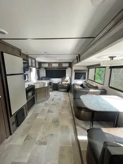 The inside of a rv with a living room , dining room , and kitchen.