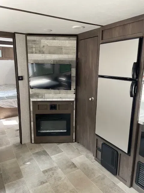 A kitchen with a refrigerator , microwave , and television