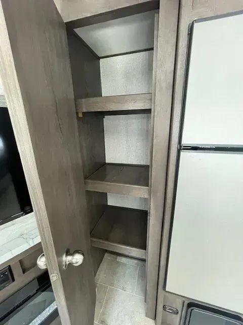 A closet with shelves and a refrigerator in a rv.