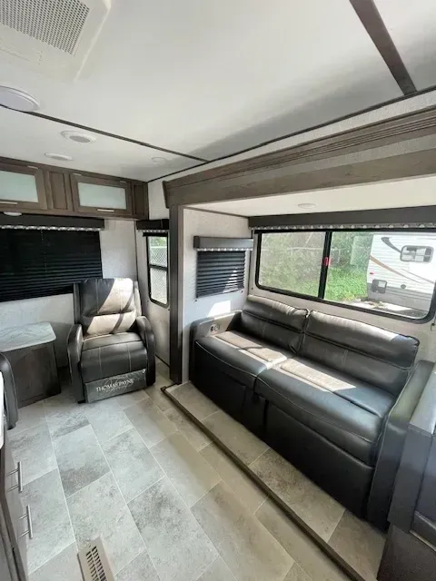 A living room in a rv with a couch and chairs.