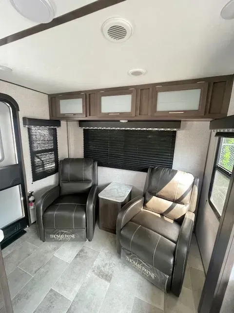 A living room in a rv with two chairs and a table.