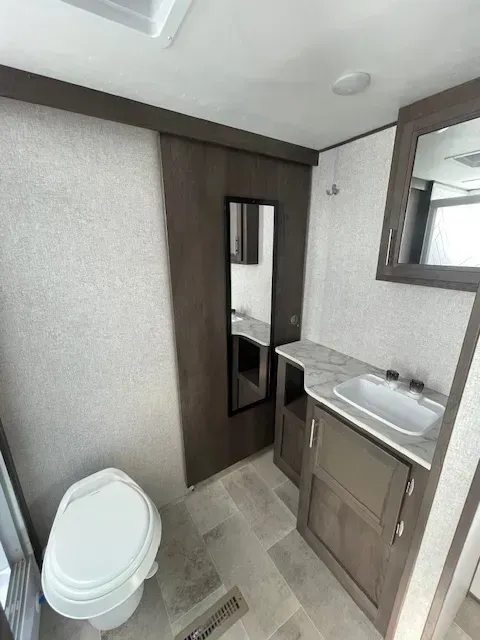 A bathroom with a toilet , sink and mirror.