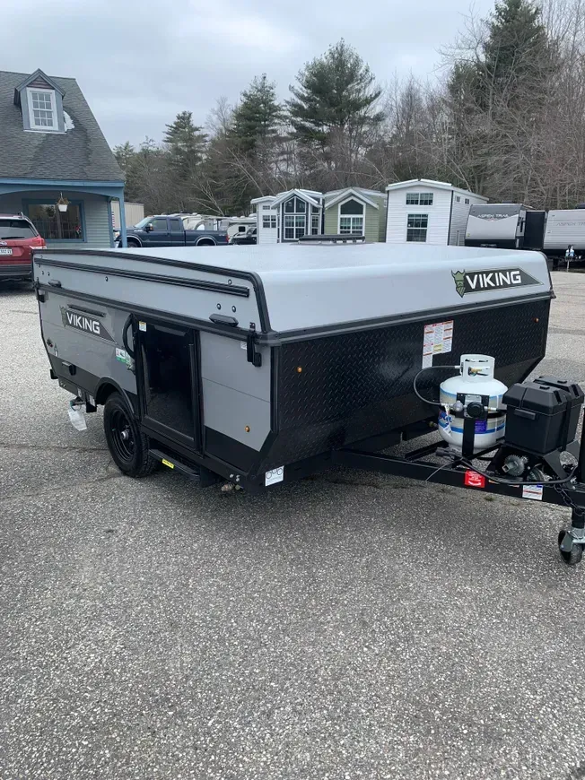 A camper trailer is parked in a parking lot next to a building.