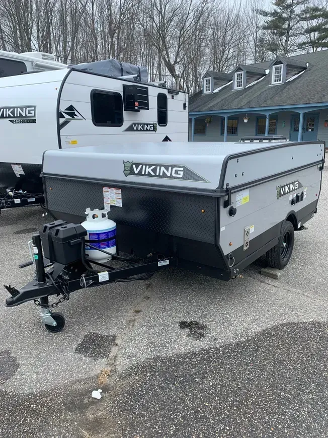 A viking pop up trailer is parked in a parking lot next to a rv.