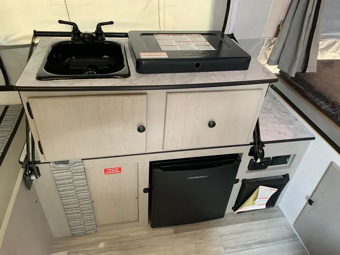 A small kitchen in a camper with a sink and a refrigerator.
