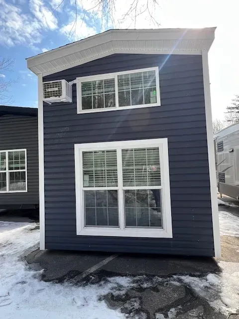 A small house with a lot of windows is sitting in the snow.