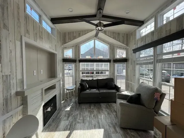 A living room with a couch , chair , fireplace and lots of windows.