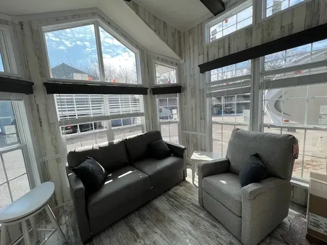 A living room with a couch and chair and lots of windows.