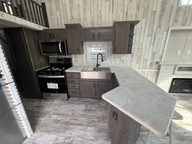 A kitchen with a sink , stove , microwave and refrigerator.