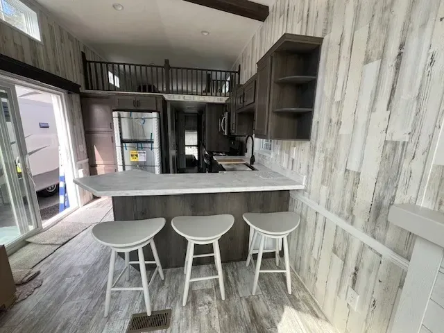 A kitchen in a mobile home with a bar and stools.