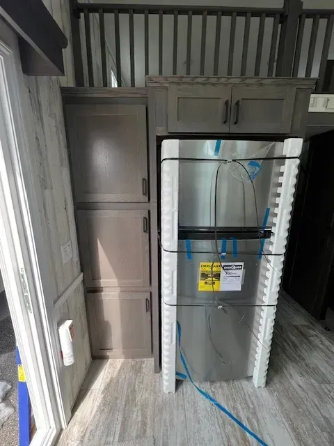 A stainless steel refrigerator is sitting in a kitchen next to a sliding glass door.