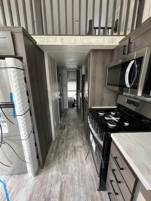 A kitchen with a stove , microwave and refrigerator.