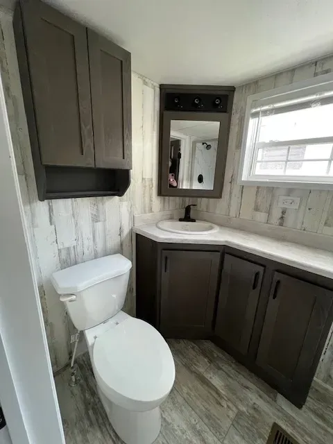 A bathroom with a toilet , sink and mirror.