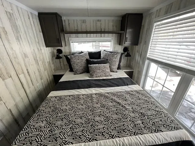 A bedroom with a bed and a window with blinds.