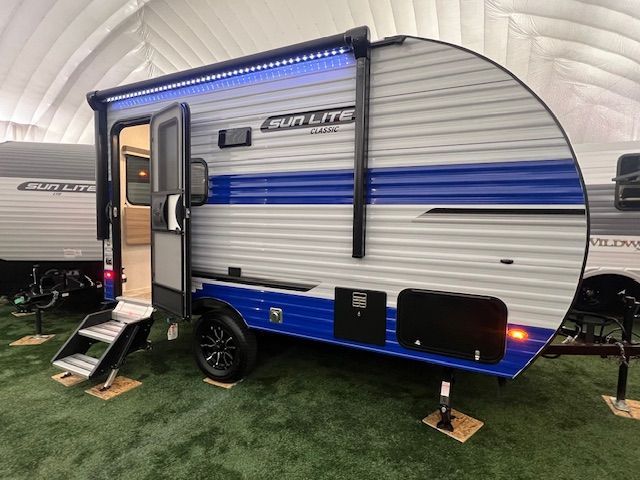 A blue and white RV is parked on top of a lush green field.