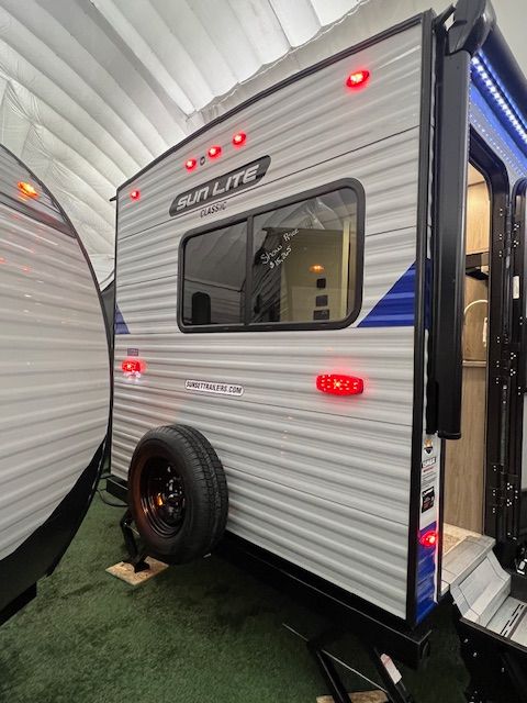 A blue and white RV is parked in a tent.