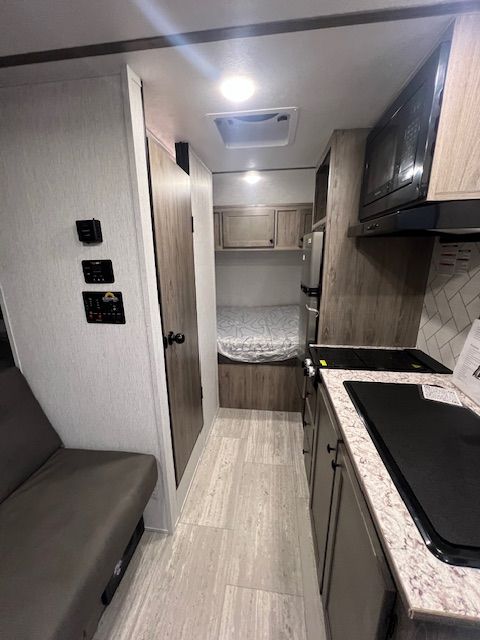 A kitchen in an RV with a bed in the back.