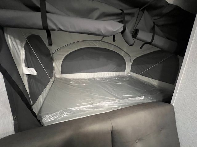A bed in a camper with a tent on top of it