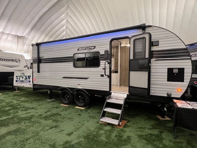 A small trailer is parked in a tent on top of a lush green field.