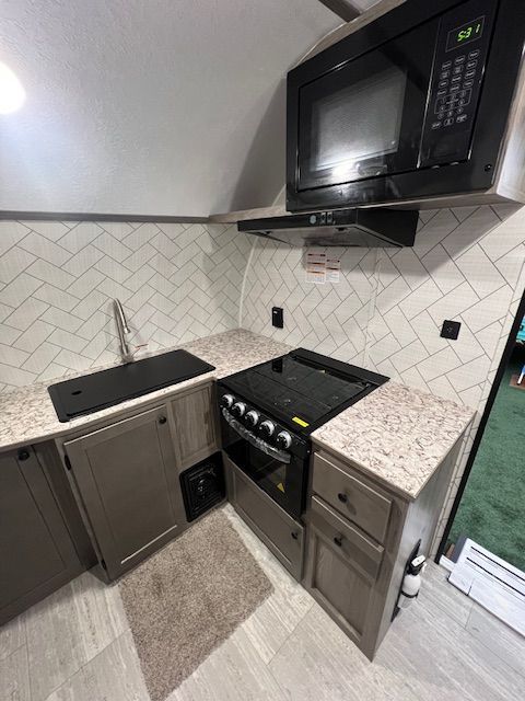 A kitchen with a stove, microwave, and sink.