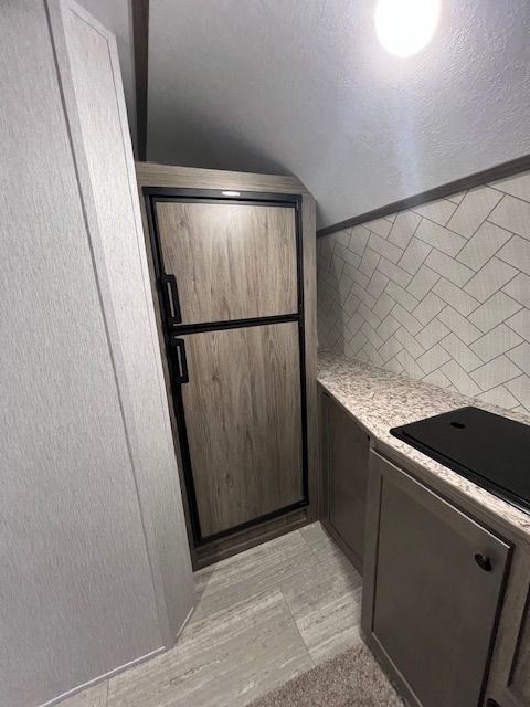 A kitchen with a refrigerator and a stovetop oven.