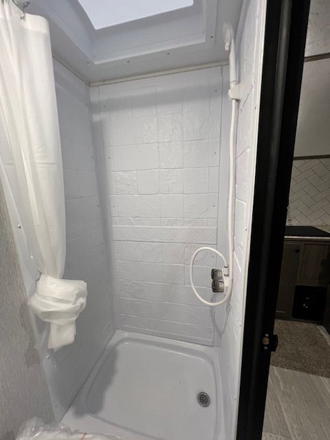 A bathroom with a shower and a skylight.