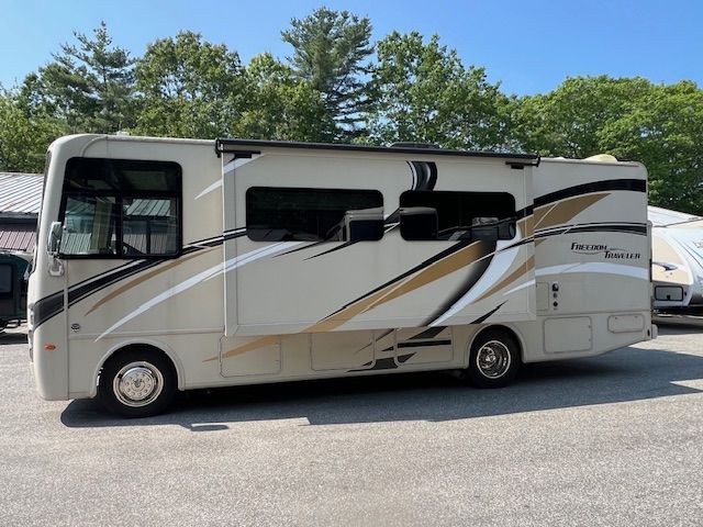 A white and gold RVis parked in a parking lot