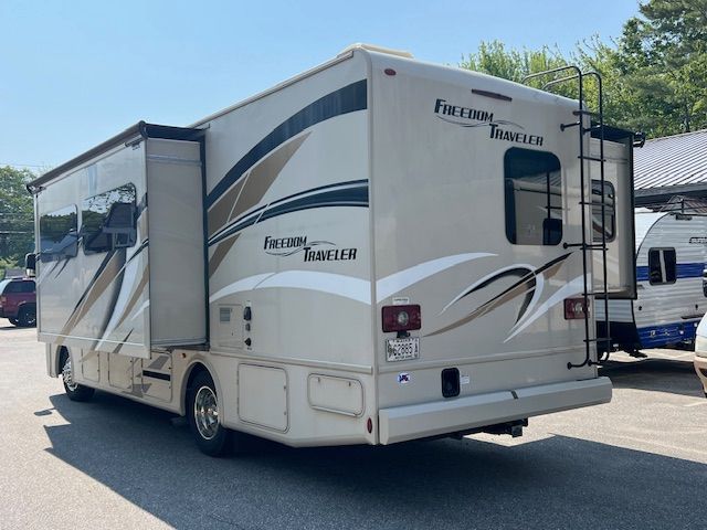 A white RV is parked in a parking lot