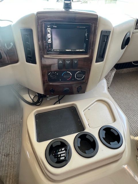 A dashboard of a vehicle with a TV and cup holders