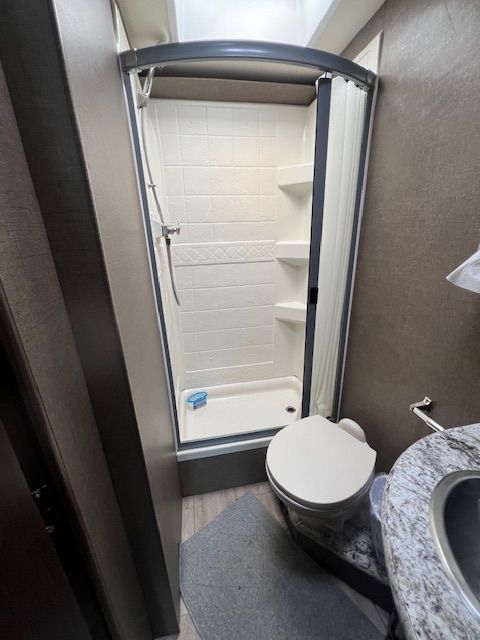 A bathroom with a toilet, sink, and shower.