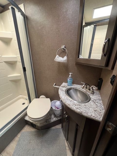 A bathroom with a toilet, sink, and shower.