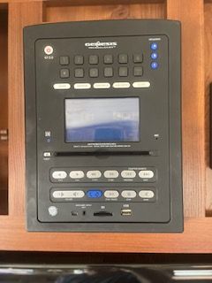 Black Genesis RV entertainment control panel with buttons, screen, and media ports.
