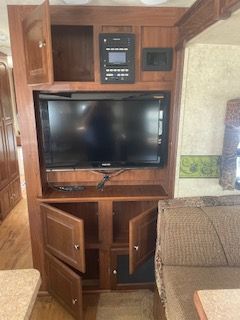 RV entertainment center with TV, cabinet, and control panel.