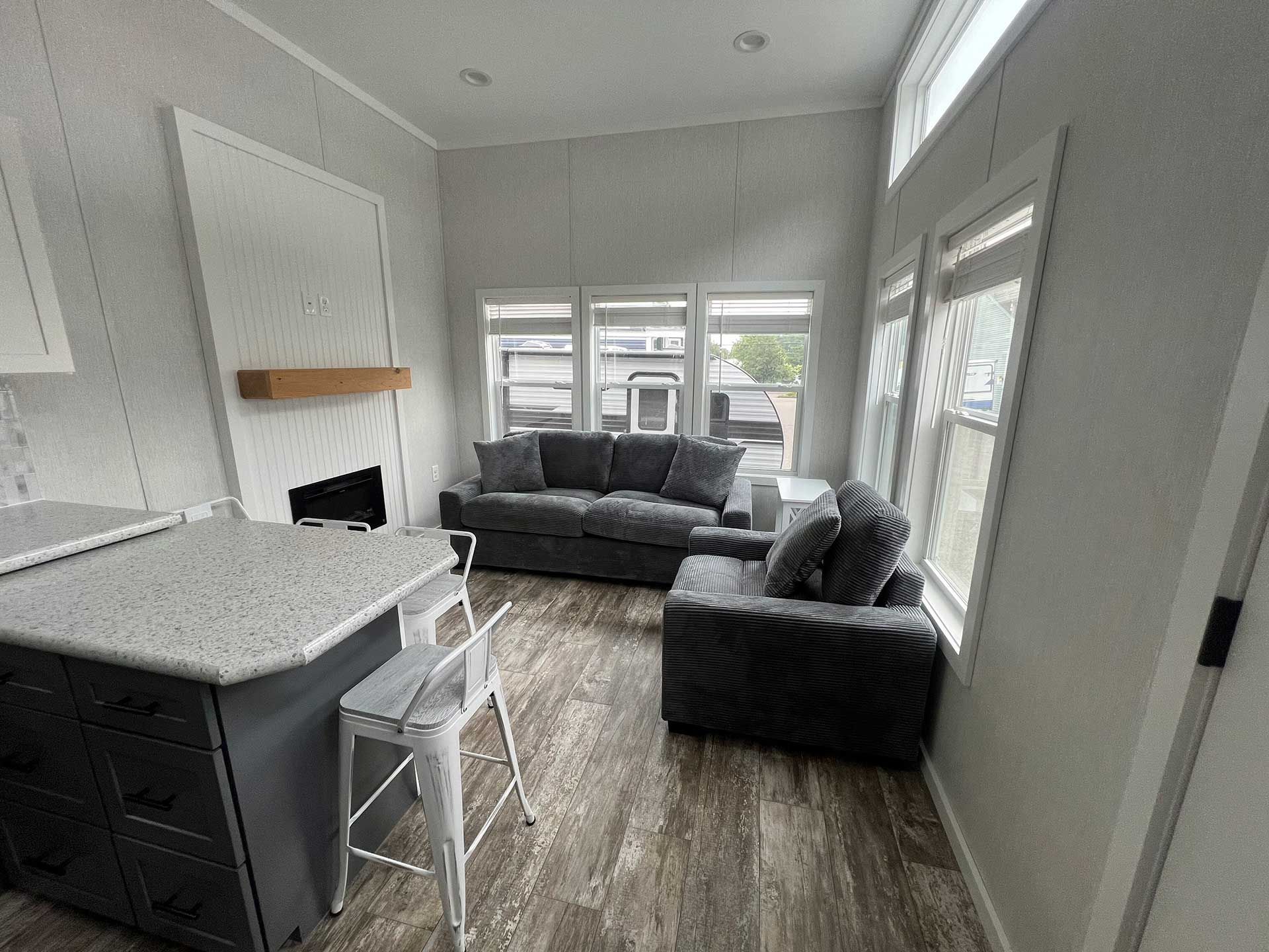 a modern living room with gray furniture, a fireplace, and large windows