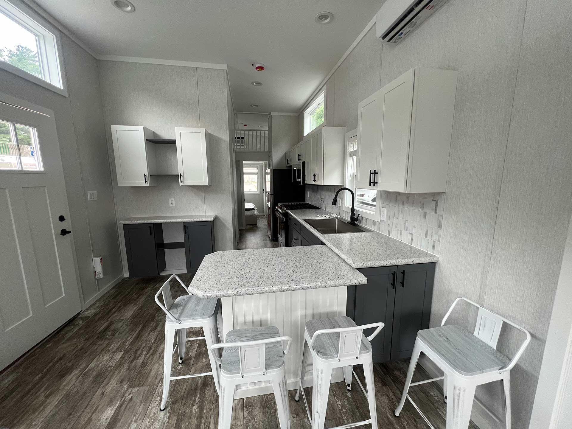 modern tiny house interior with kitchen, cabinets, island, and bar stools