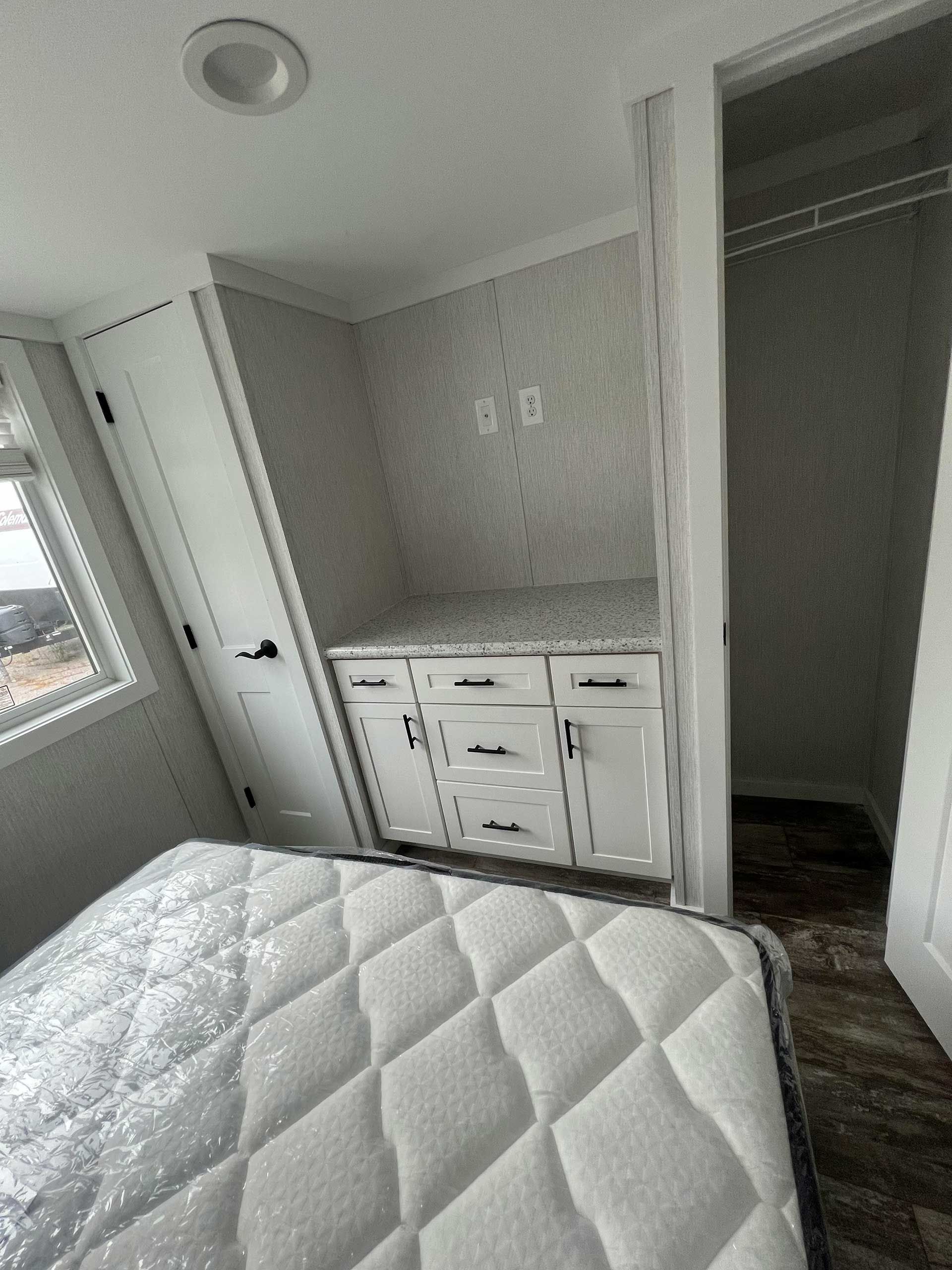 bedroom interior with built-in cabinets, closet, window, and a bed with a white mattress