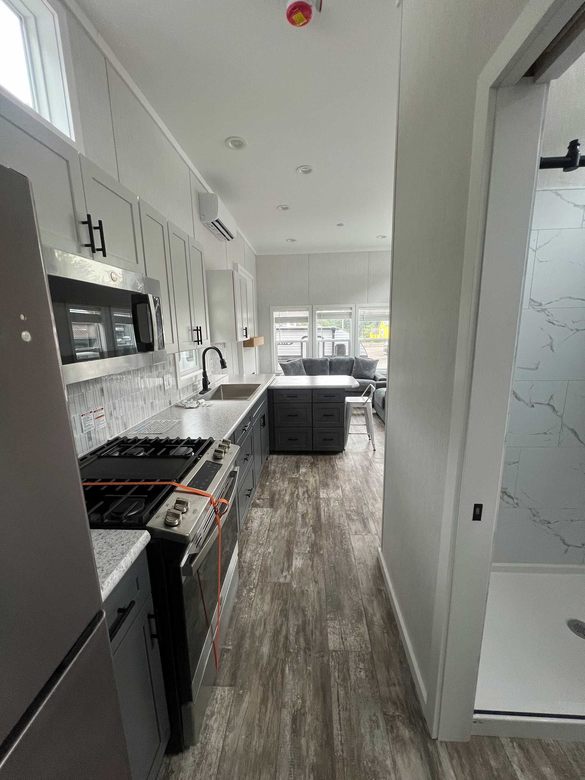 narrow modern kitchen with gray cabinets, stainless steel appliances, and wood-look flooring