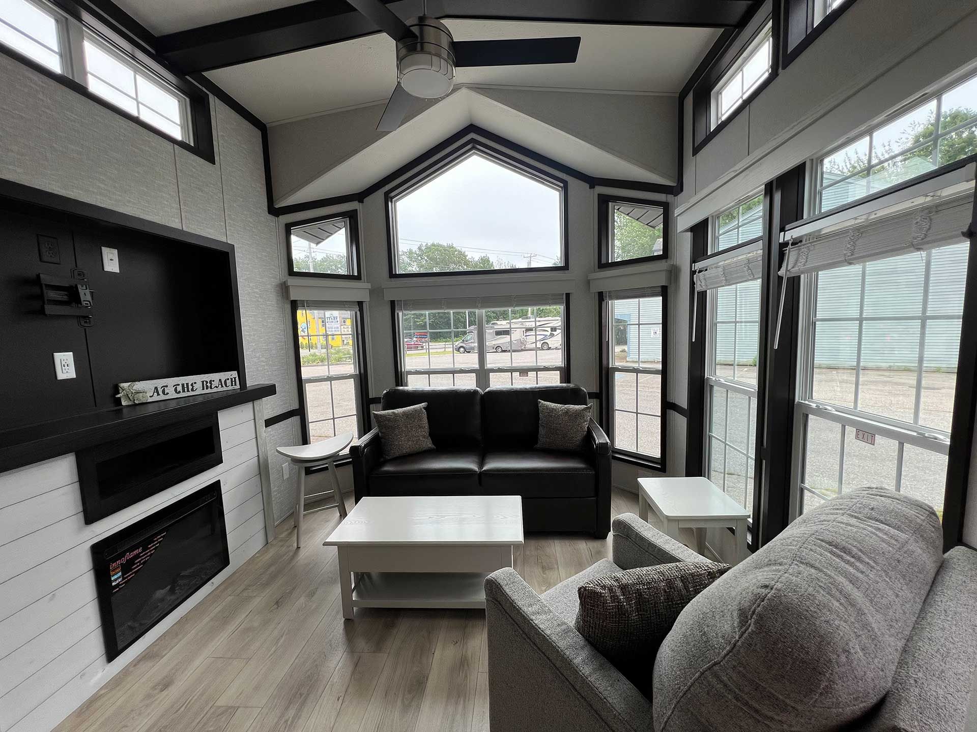 living room with black couch, gray chair, white table, fireplace, large windows