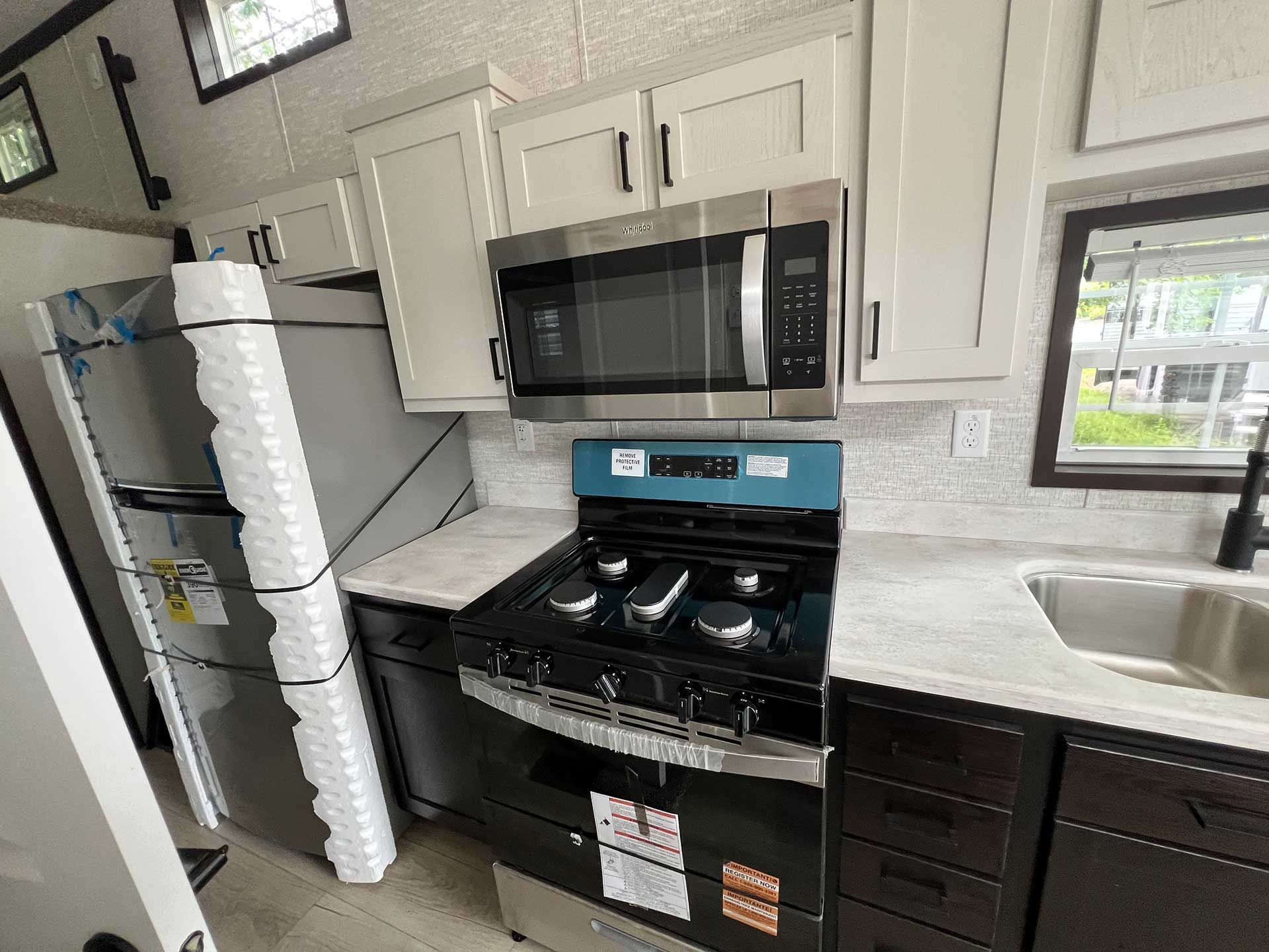 kitchen with stainless steel appliances, light cabinets, dark lower cabinets, and a window