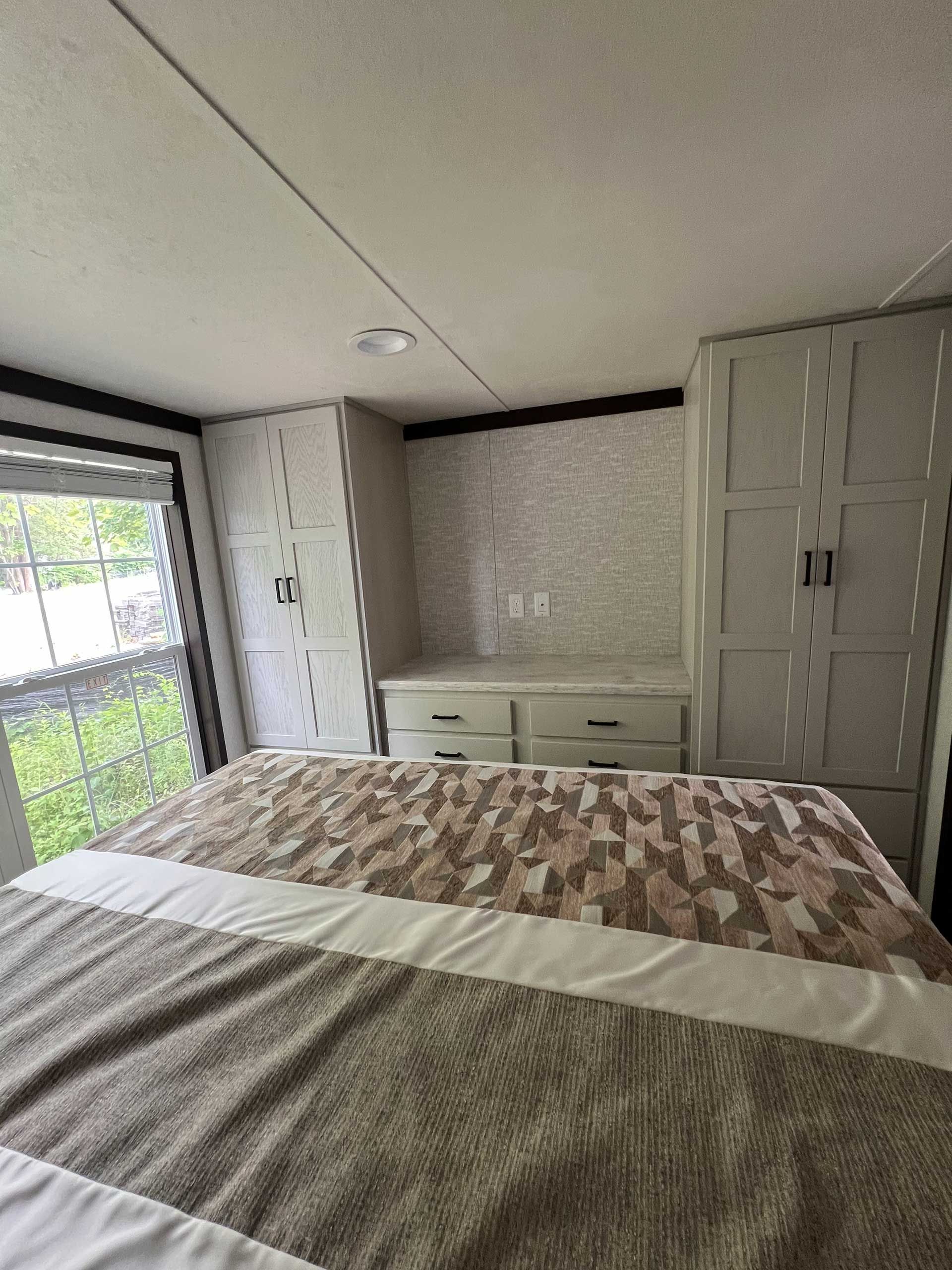 bedroom with a bed, cabinets, and a window; gray and beige color scheme