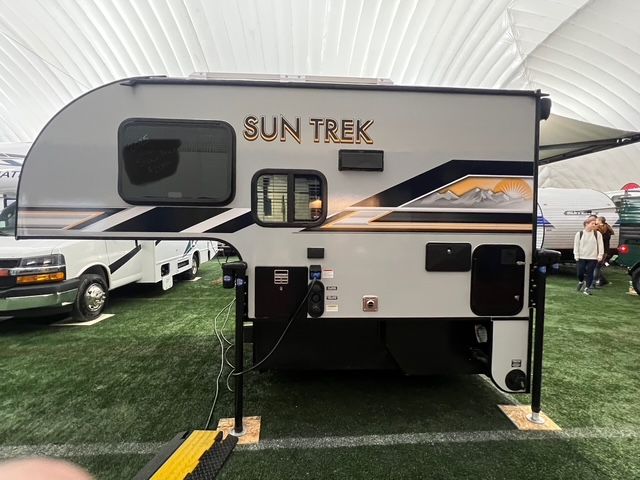 A Sun Trek Camper is parked in a grassy field