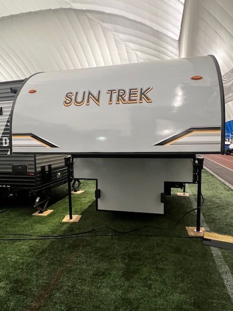 A Sun Trek Trailer is sitting on top of a lush green field.